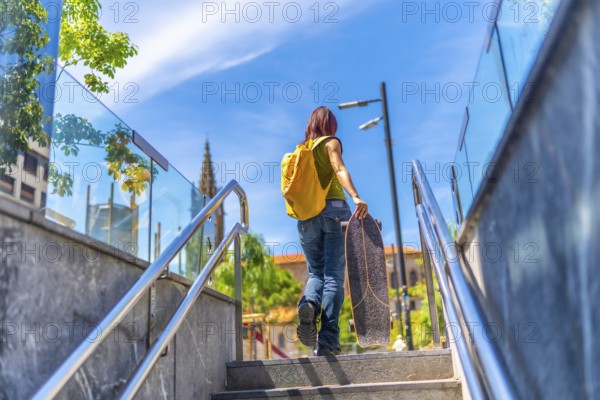 Low angle view photo of the rear view of a young woman with casual denim clothes and a bag carrying