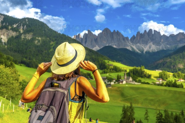 Female tourist holding her hat while admiring the stunning view of the odle mountains and santa