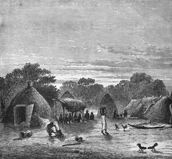 Village view with huts in the tropics, locals sitting in the shade, woman carrying a bowl on her