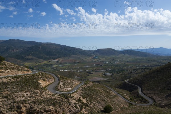 Mountain landscape with serpentine road in green valley under blue sky with clouds, road to Mirador