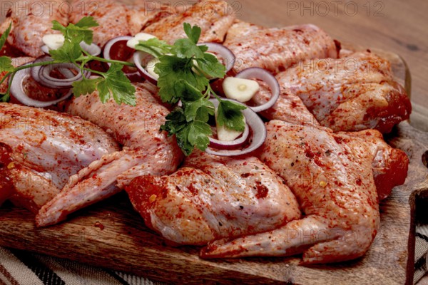 Chicken wings, marinated and laid out on a wooden platter, ready for cooking, grilling or baking,