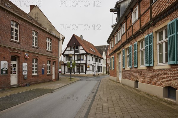 Historic brick houses with white windows and shutters and a small half-timbered house in Warendorf,