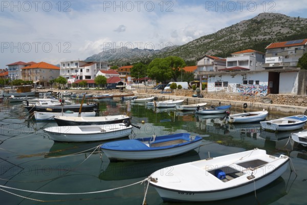 Various boats in a harbour surrounded by mountains and a quiet village panorama, Starigrad,