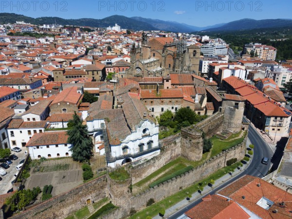 Historic buildings with red tiled roofs and castle walls in a town on a sunny day, aerial view,