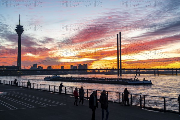 Winter sunset on the Rhine near Düsseldorf, riverside promenade at the old town, Rhine Tower, cargo