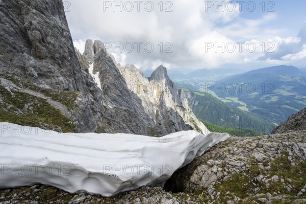 Residual snow in a saddle in spring, rocky mountain landscape, ascent to the summit of the