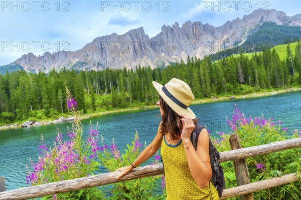 Woman enjoying the landscape of lake carezza with the latemar mountain range in the background,
