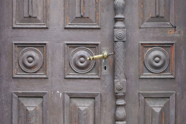 Old antique wooden door with decorative round patterns and a metal door handle, St. Martin,