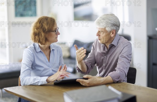 Symbolic photo. A woman and a man sit together at a table with a tablet and talk. Berlin, 13.08