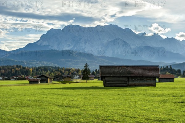 Green meadow with hay huts, behind Kranzberg, mountains Obere Wettersteinspitze, Rotplattenspitze,