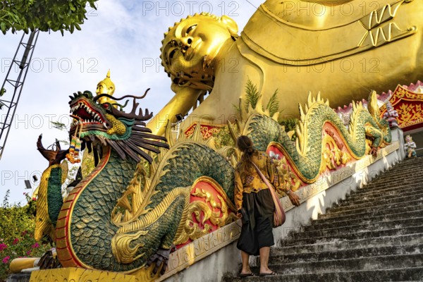 Tourist in front of the huge reclining Buddha statue of the Buddhist temple Wat Mokkanlan in Chom