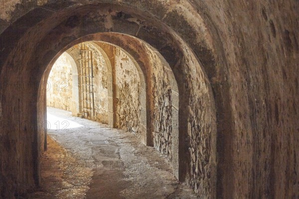An old, dark tunnel with stone walls and a glow of light at the end, Venetian Sea Fortress, Leper