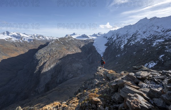 Mountaineer standing on a rock, surrounded by an impressive mountain landscape with snow-covered
