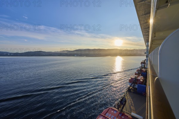 View from a cruise ship, Mein Schiff 6, of the calm sea at sunrise with soft clouds in the sky,