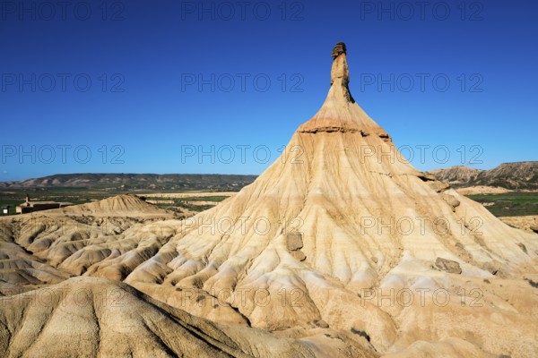 A striking rock formation in a desert landscape under a clear blue sky, Castildetierra, Bardenas