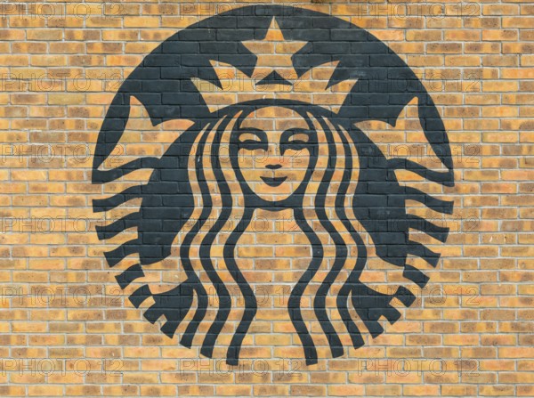 Starbucks coffee logo symbol stencilled onto wall of yellow bricks, Liverpool, Merseyside, England,