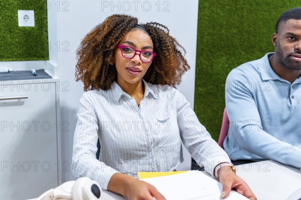 Two young professionals are working together in a modern coworking space, focused on a shared