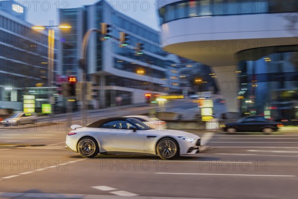 Car at night in front of urban surroundings with modern architecture, pull-along. Mercedes-Benz SL