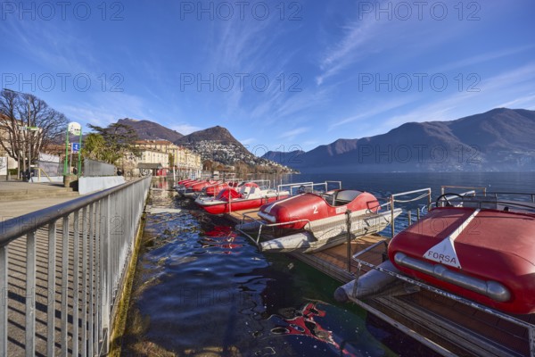 Pedal boats, metal railing, lake, shore, pavement, pedal boat rental, mountain landscape, haze,