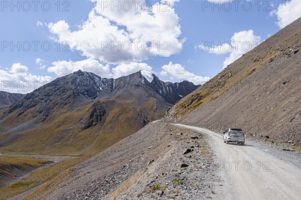 Car on narrow gravel track in mountain landscape at Chong Ashuu Pass, Tian Shan Mountains,