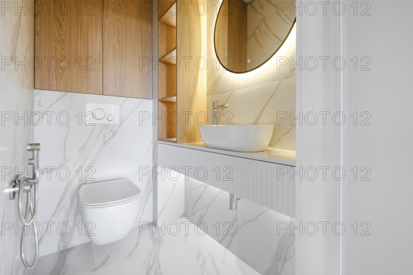 This contemporary bathroom showcases minimalistic design with marble walls and a circular mirror,