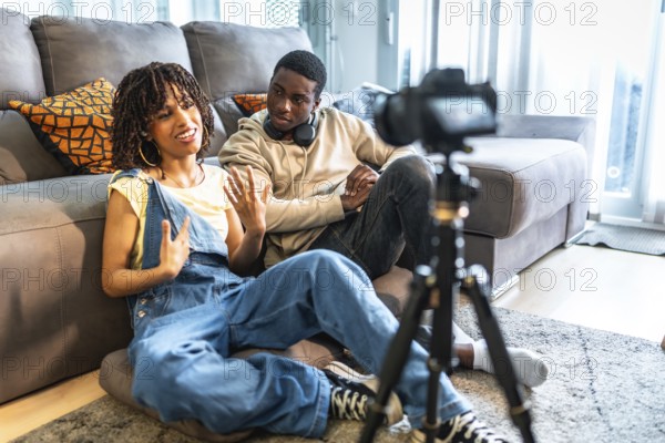 Two influencers recording a vlog in their living room, capturing authentic moments with a camera