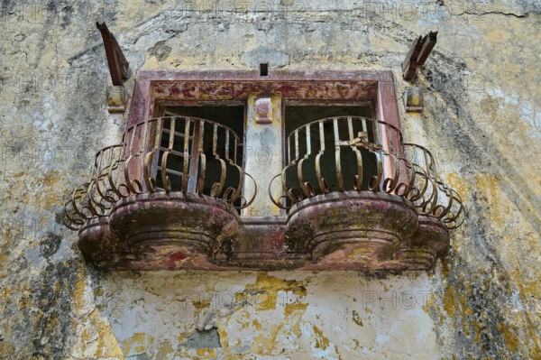 An abandoned balcony with rusty railings and damaged façade on an old building, Italian Governor's