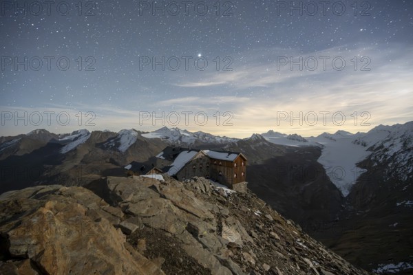 Mountain landscape under a starry sky, night shot, mountain hut Ramolhaus in autumn with snow, view