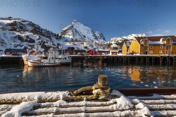 Fishing village with yellow and red houses in front of snow-covered mountains, Nusfjord,