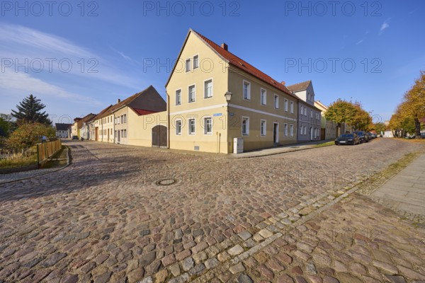 Residential building, cobblestone pavement, blue sky with cirrostratus clouds, intersection of
