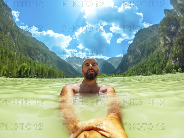 Tourist swimming in the crystal clear waters of lago di landro, surrounded by the breathtaking