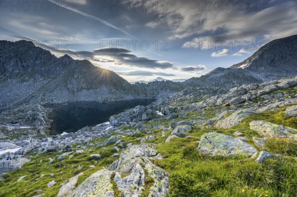 Sunrise over a mountain landscape with wo, ken rocky terrain and mountain lake, Krimml, Salzburg,