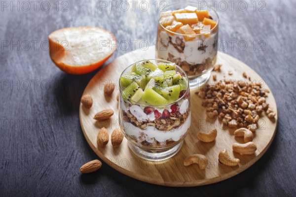 Dessert with greek yogurt, granola, almond, cashew, kiwi and persimmon on wooden background. close