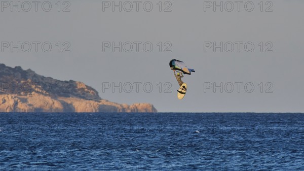 Wingfoiller, surfer in the air over the sea near a coast with cliffs, windsurfer, Meltemi