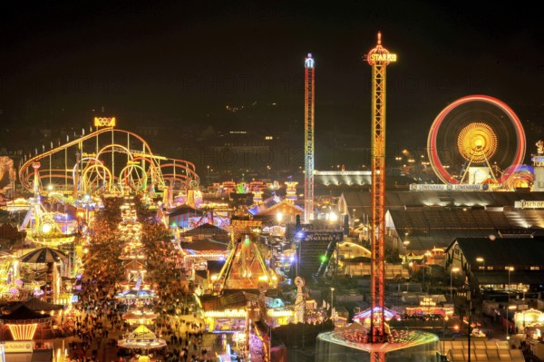 Street of beer tents, main street at night with illuminated roller coaster, Ferris wheel, stalls,