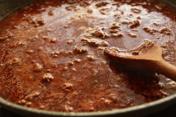 Cooking, bolognese sauce, in a frying pan, stirring with a wooden spoon, tomato meat sauce,