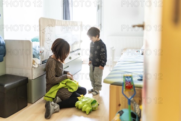 Mother and son playing together at home, preparing a dinosaur costume for a fun game in their