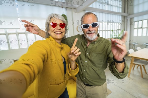 Frontal personal point of view of a happy senior couple with fun sunglasses taking selfie at
