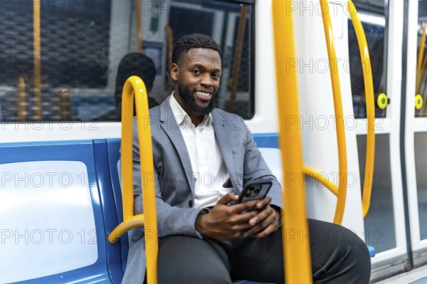 Young professional enjoying his commute, using a smartphone while traveling through the metro,