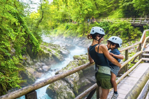 Mother holding her son while enjoying the breathtaking view of the turquoise radovna river flowing