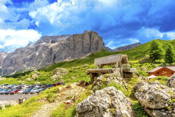 Weathered wooden bench inviting rest while offering breathtaking views of sella pass in the italian