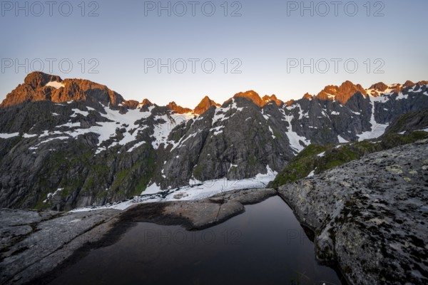 Rocky mountain peaks and Trollfjordvatnet with snow, small pond in moorland at Trollfjord Hytta,