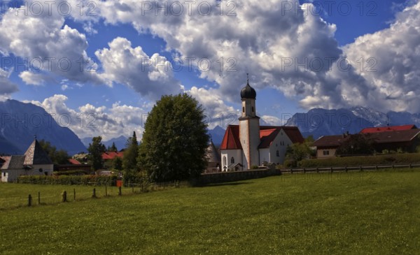 Idyllic village with church and mountains in the background under a blue sky, Wallgau, Bavaria,