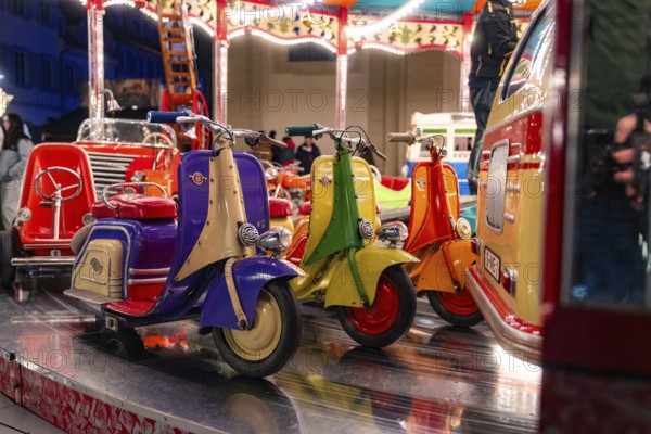 Colourful toy scooters on a fairground carousel at night, Christmas market Ludwigsburg, Germany,