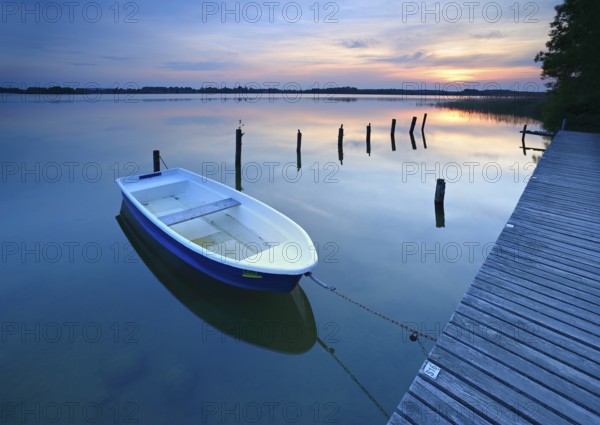 Sunset at Lake Schaalsee, jetty with rowing boat and wooden post in the water, Schaalsee Biosphere