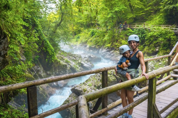 Mother carrying her child while visiting the stunning vintgar gorge near bled, slovenia, enjoying a