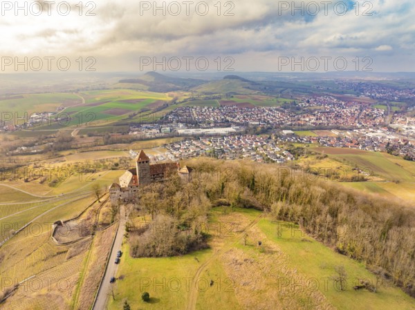 Aerial view of the castle with surrounding dense forests and a neighbouring village under a cloudy