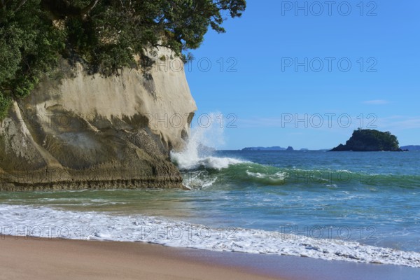 Breaking waves with spray in front of mighty cliffs by the sea, Cathedral Cove, Hahei, Coromandel