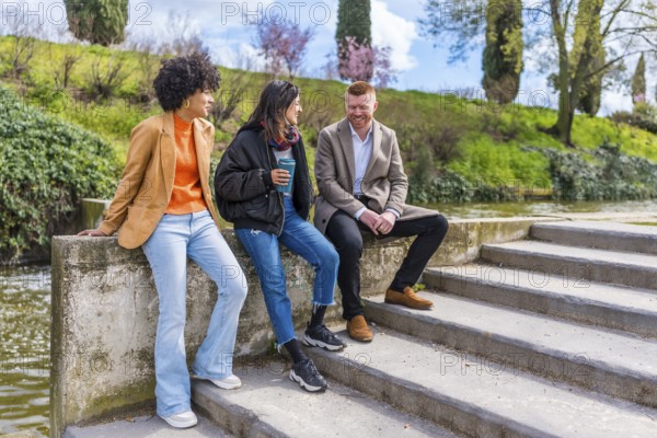 Three young professionals enjoying a break, chatting and laughing together by a canal in a city