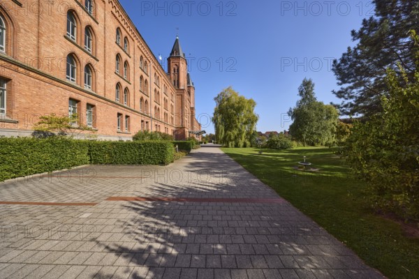 New town hall, brick building, architectural style neo-Gothic, former barracks, hedge, trees, blue